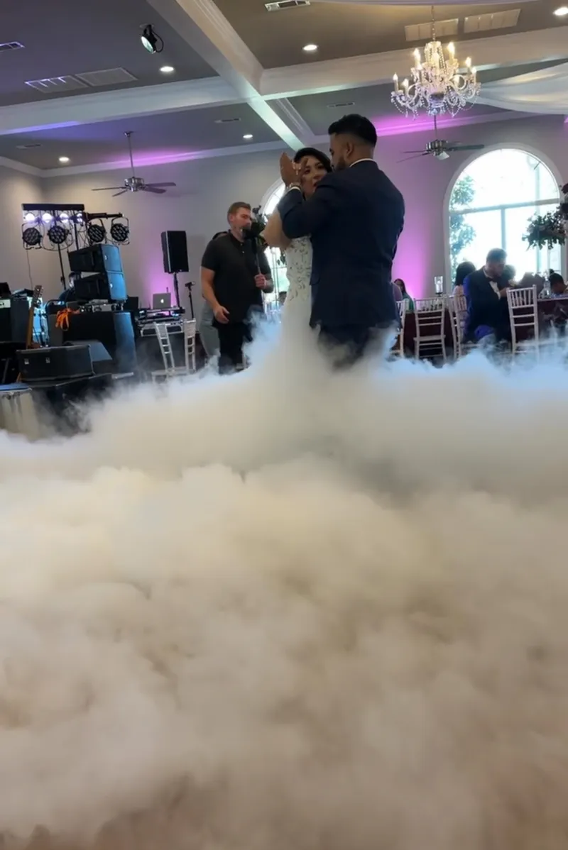 Los novios comparten un momento de Dance on the Clouds durante su primer baile en una pista de baile cubierta de niebla en una recepción de boda de DJ Oso